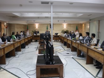 مجموعة من الأشخاص يجلسون على طاولات طويلة في غرفة بها أجهزة كمبيوتر